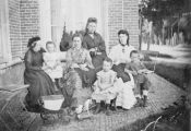 Groepsfoto van de familie naast het huis van familie Bolsius. Rechts de ingang van het Nederlands Hervormde kerkje. Voor meer details klik hier.